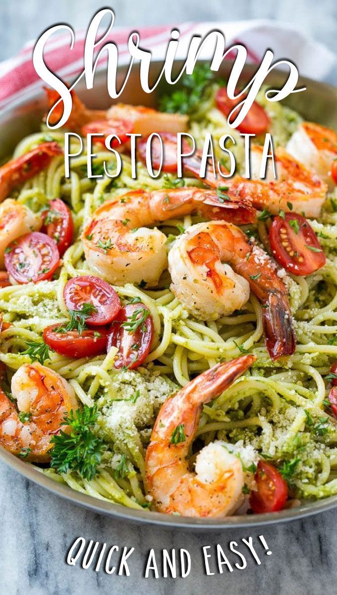 shrimp pesto pasta in a pan with tomatoes and parsley