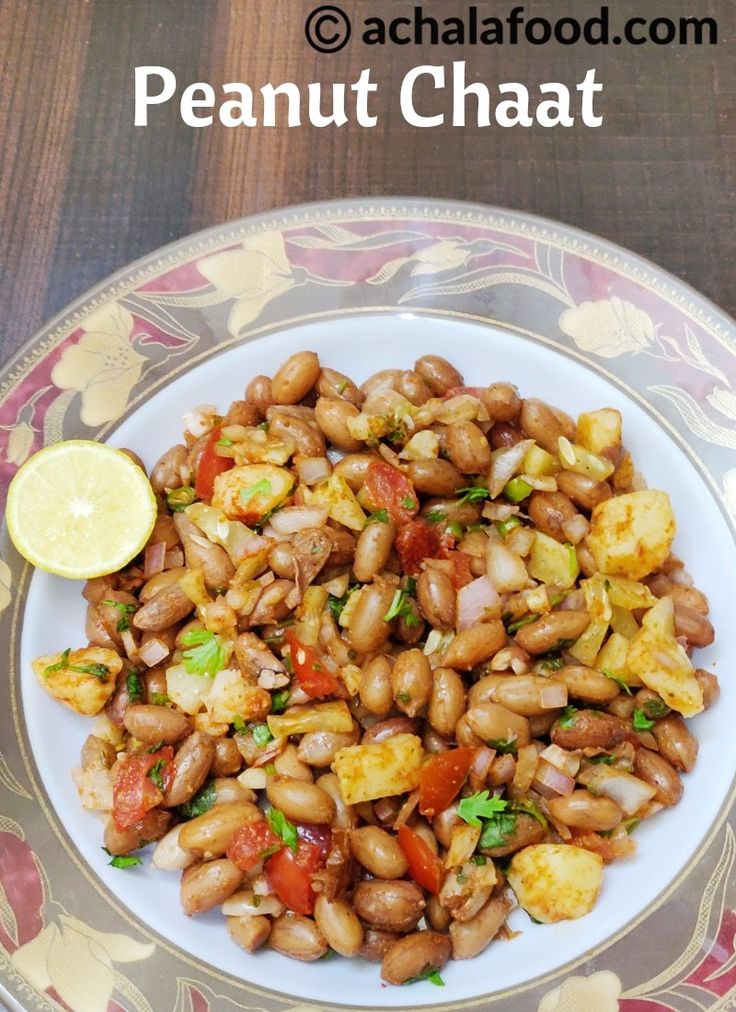 a white plate topped with beans and veggies next to a slice of lemon