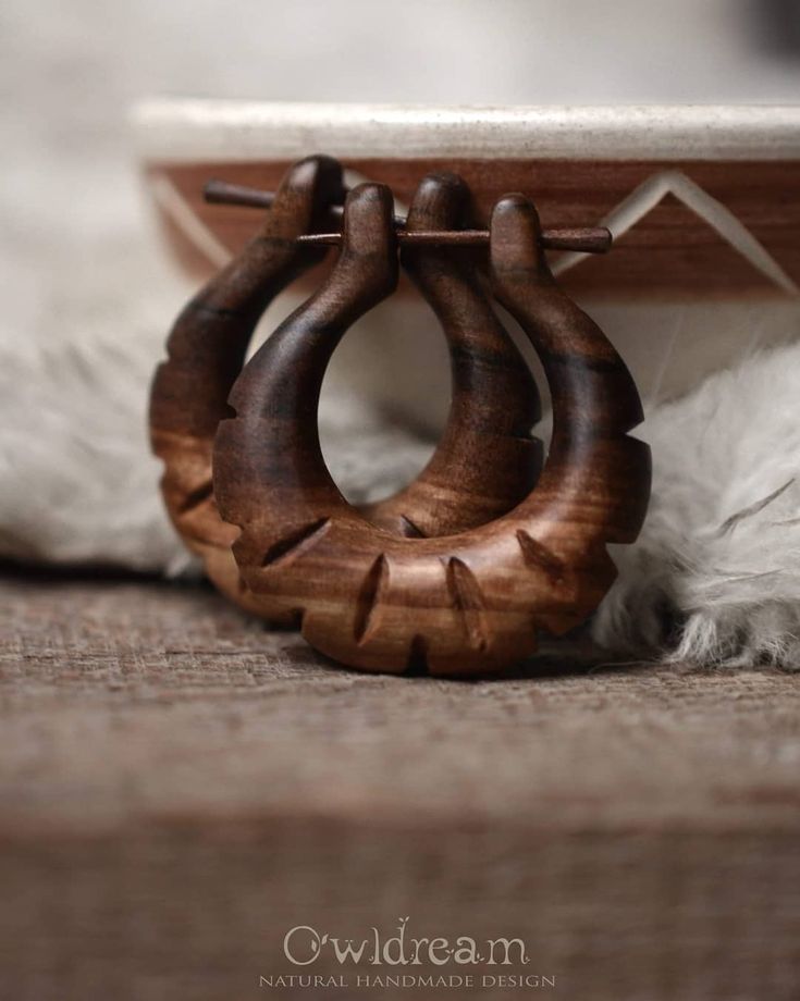 a pair of wooden hoop earrings sitting on top of a rug