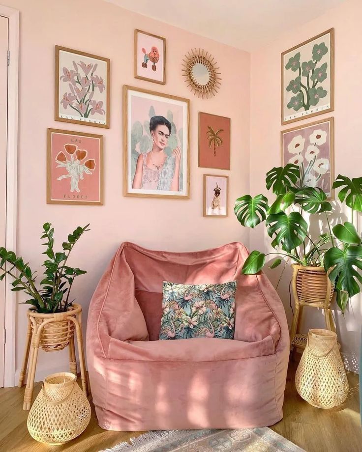 a living room with pink walls and pictures on the wall, plants in vases