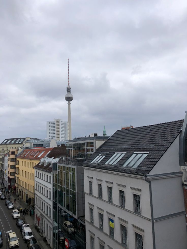 a city street filled with traffic next to tall buildings and a television tower in the distance