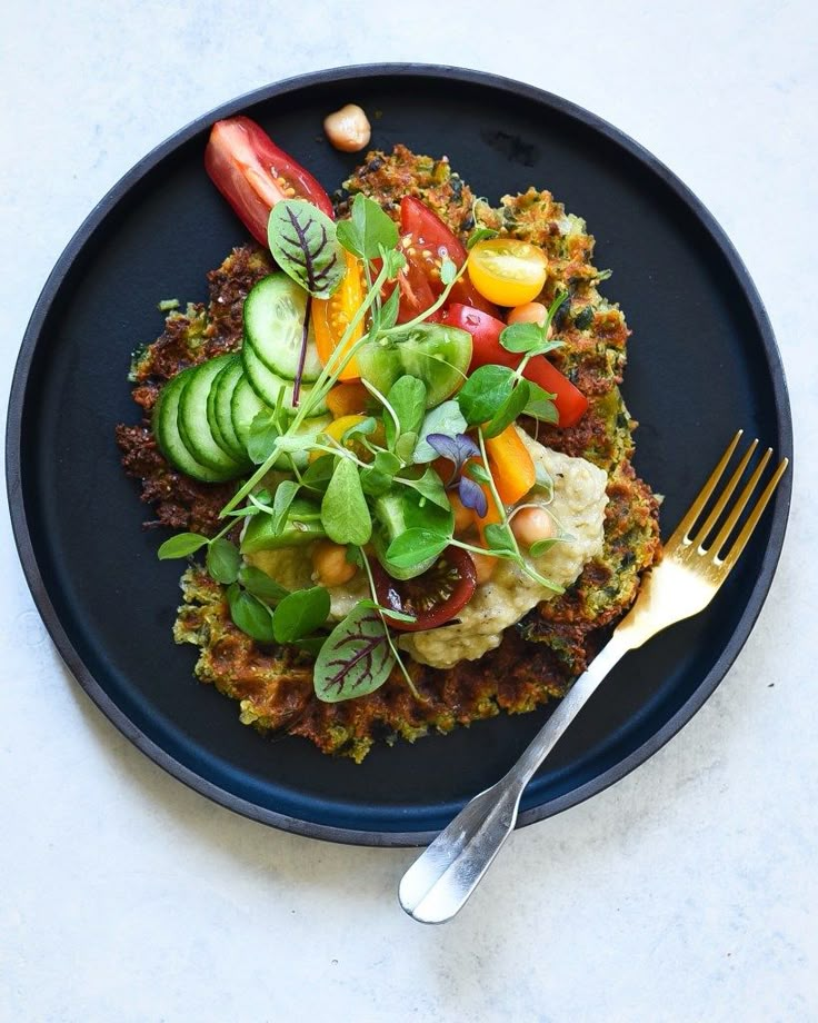 a black plate topped with food and a fork