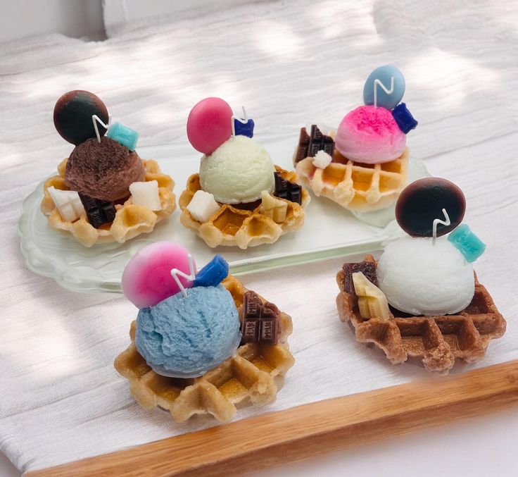 four waffles topped with ice cream and toppings on a plate next to a cutting board