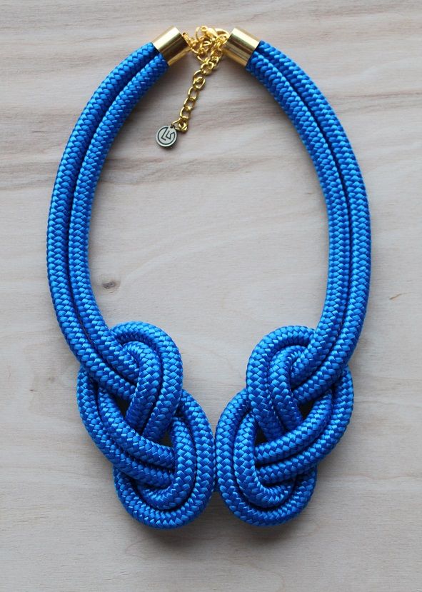 a blue rope necklace with gold accents on a wooden surface