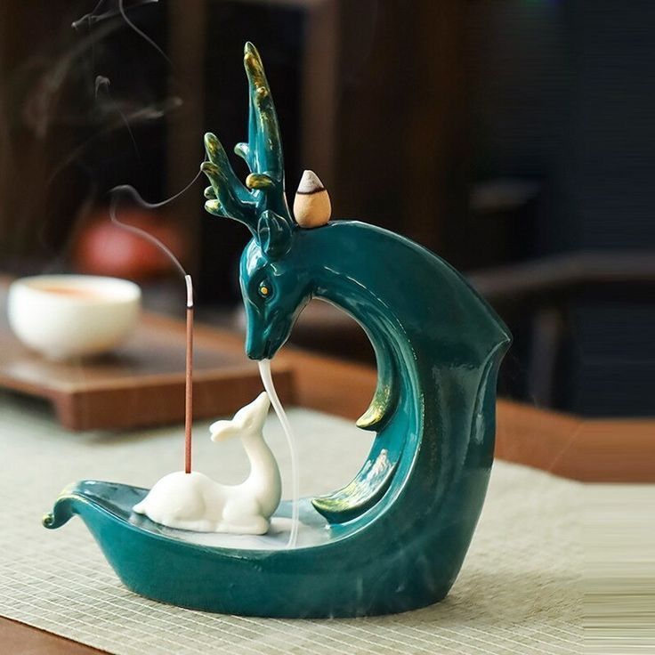 a figurine sitting on top of a wave with a candle in the shape of a dragon