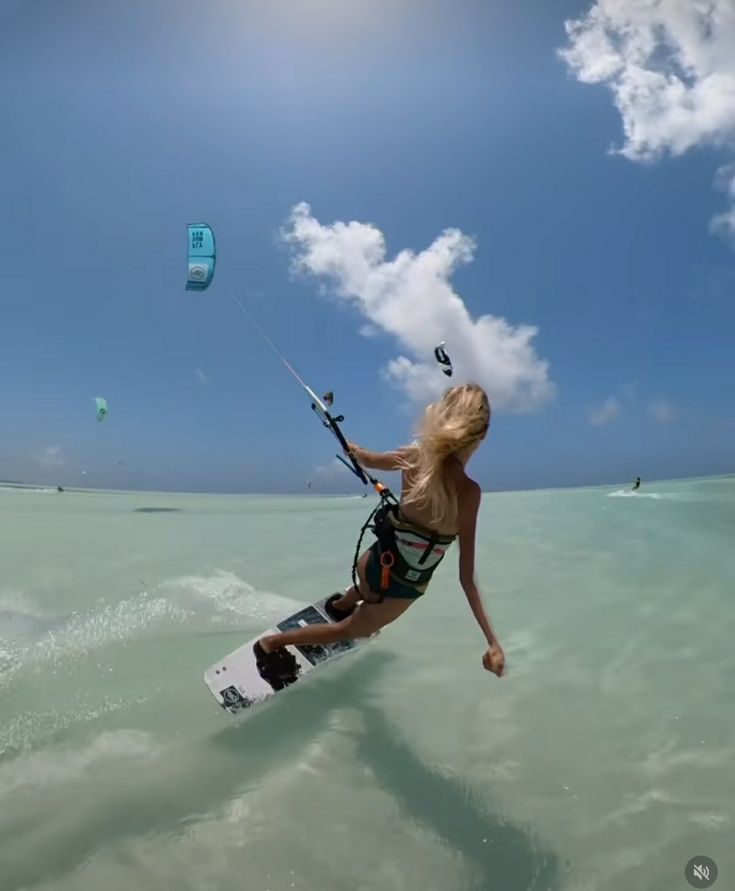 a woman is parasailing in the ocean on a sunny day with blue skies