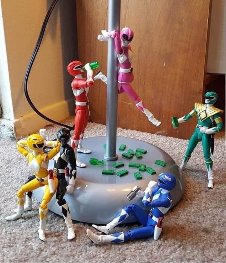 several toy action figures are posed on the floor next to a lamp post and wall