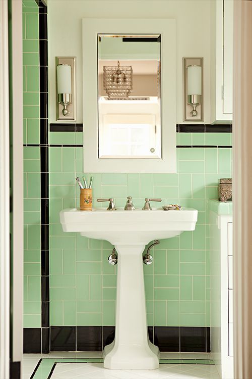 a white pedestal sink sitting under a mirror next to a green tiled bathroom counter top