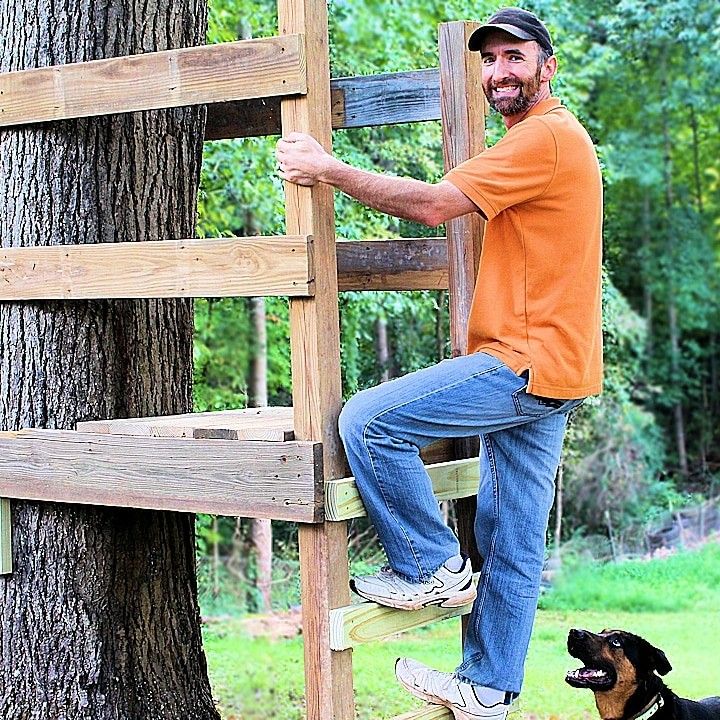 a man climbing up the side of a wooden ladder next to a black and brown dog