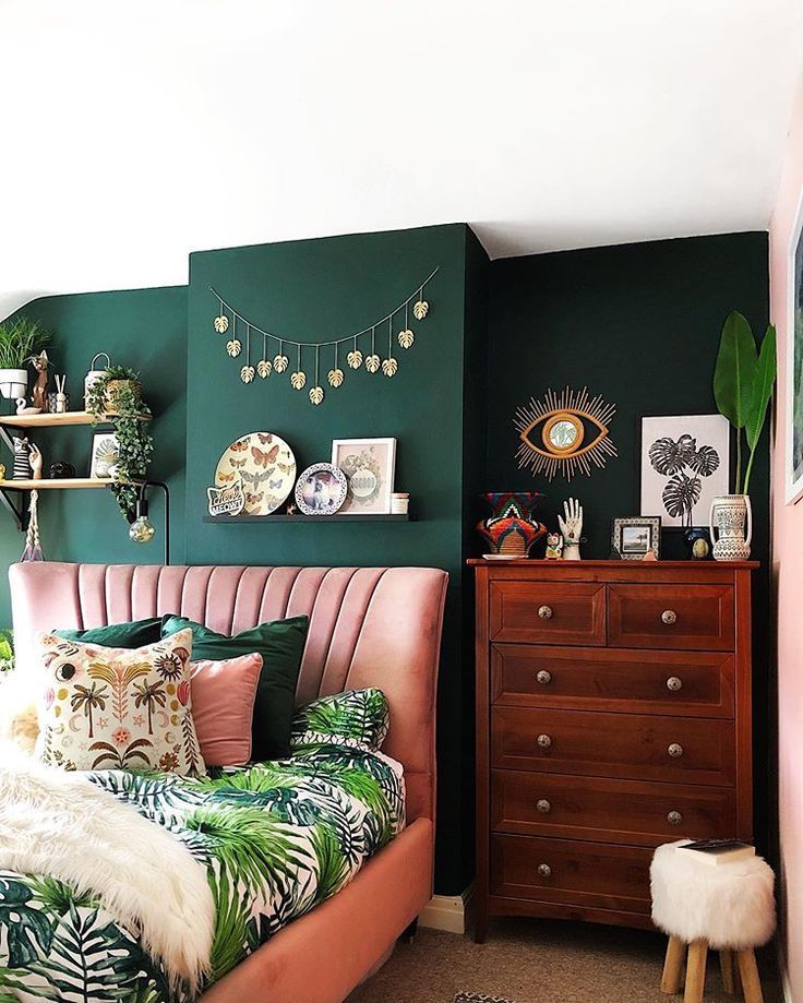 a bedroom with green walls, pink bedding and palm leaves on the headboard