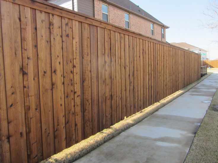 a wooden fence next to a sidewalk in front of a house