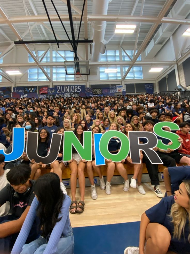 a group of people sitting in front of a sign that says juniors