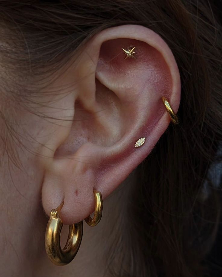 a close up of a person's ear with two small gold hoops on it