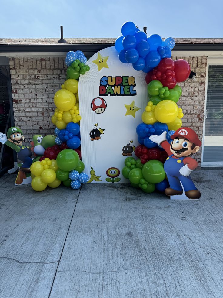 an entrance to a building decorated with balloons and mario kartman character figurines