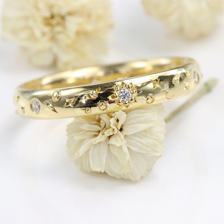 a close up of a gold ring on a white surface with flowers in the background