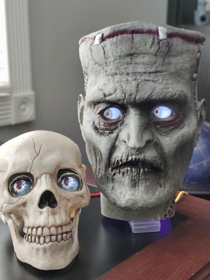 two halloween masks sitting next to each other on a table