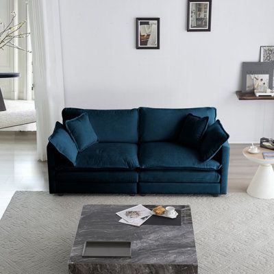 a living room with a blue couch and coffee table in front of a white wall