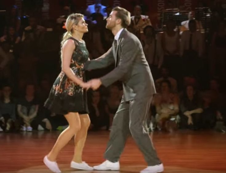 a man and woman dancing on stage in front of an audience with their hands together