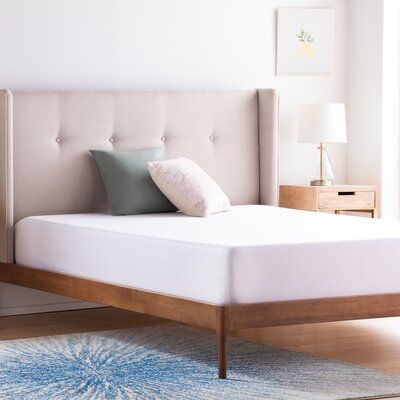 a bed with a wooden frame and headboard is shown in this room, it has a blue rug on the floor