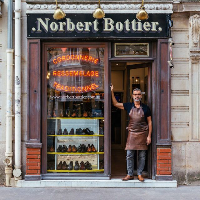 a man standing in front of a shoe store with his hand up to the door