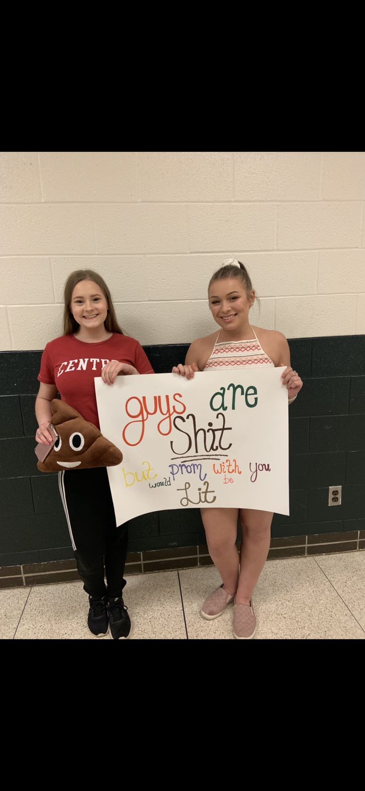 two girls holding up a sign in front of a wall