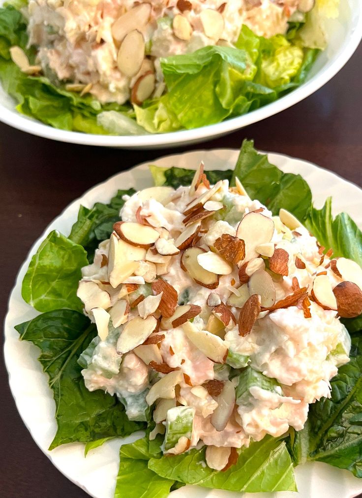 two white plates filled with salad on top of a wooden table