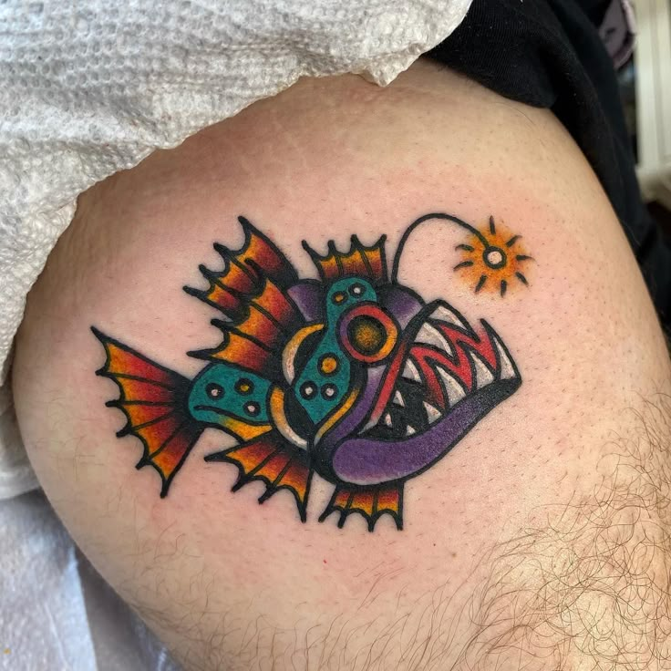 a man's thigh with a colorful fish tattoo on it