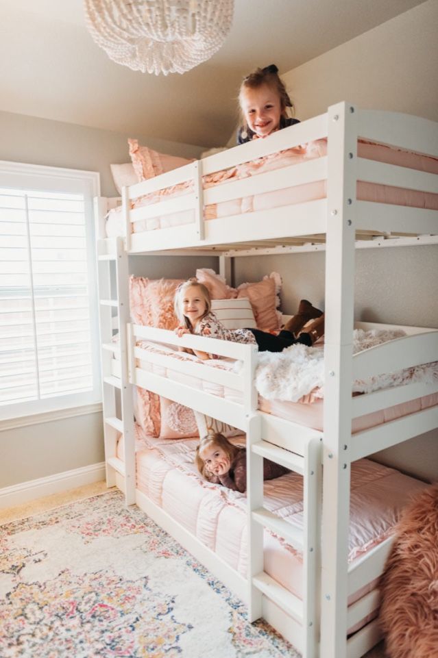 two children sitting on top of bunk beds in a room with carpet and rugs