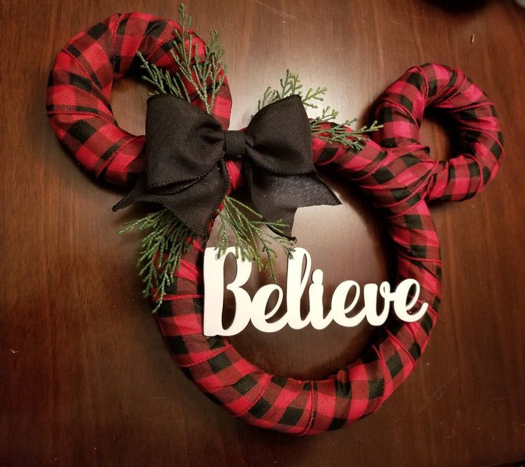 a mickey mouse wreath with the word believe on it and a bow hanging from it