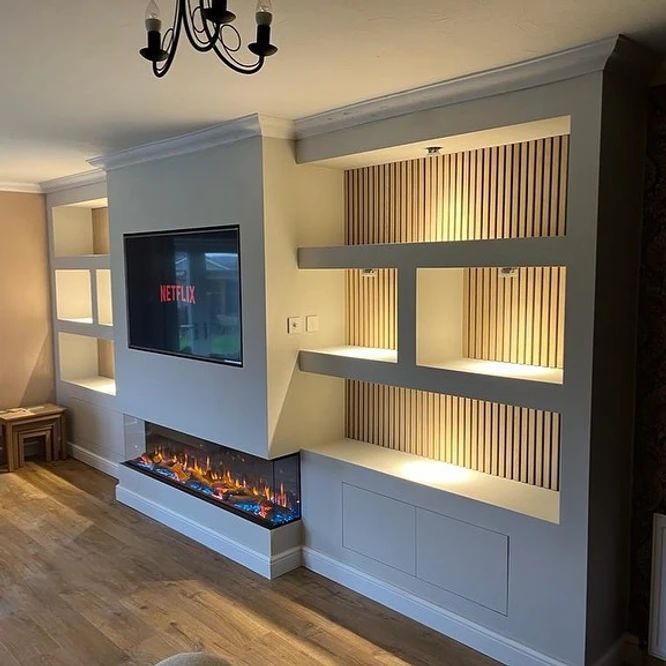 a living room with a fireplace and built in shelving units on either side of the wall