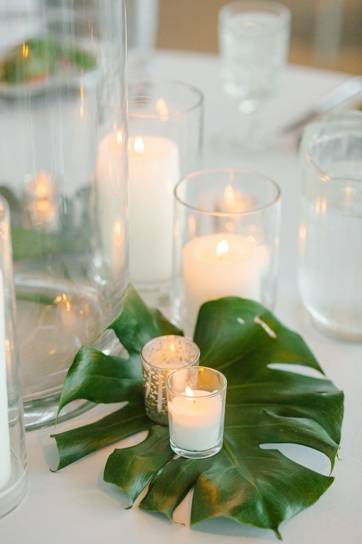 a table with candles and green leaves on it