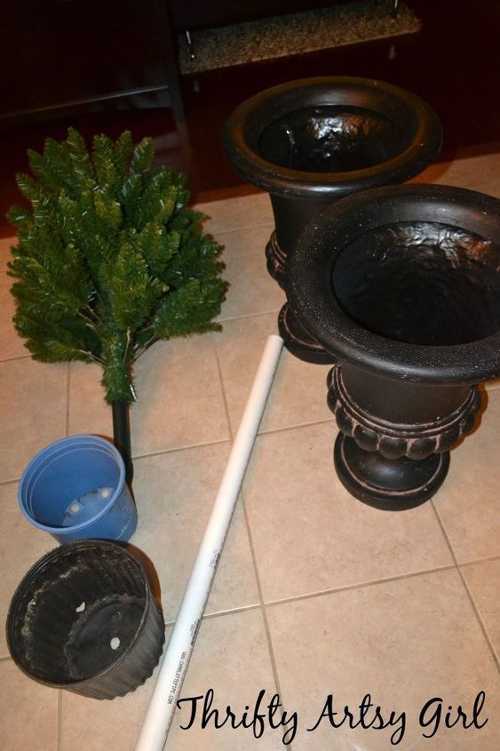 there is a potted tree next to two urinals on the floor