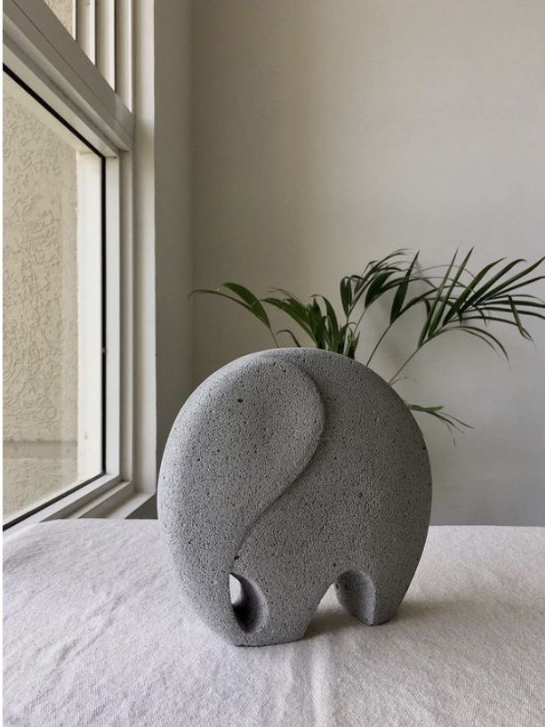 an elephant shaped vase sitting on top of a table next to a potted plant