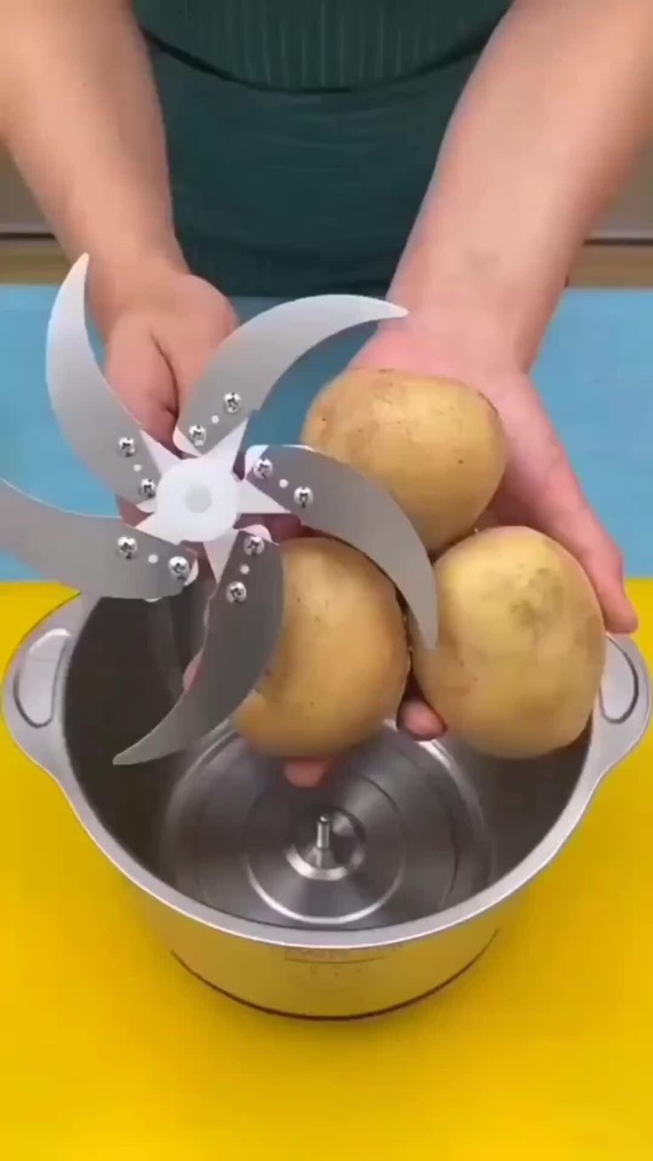 a person holding some potatoes in a pot with a propeller on it's side