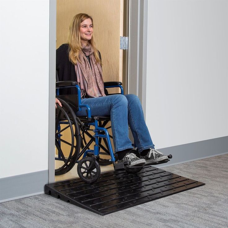 a woman sitting in a wheel chair at the entrance to an office building, smiling