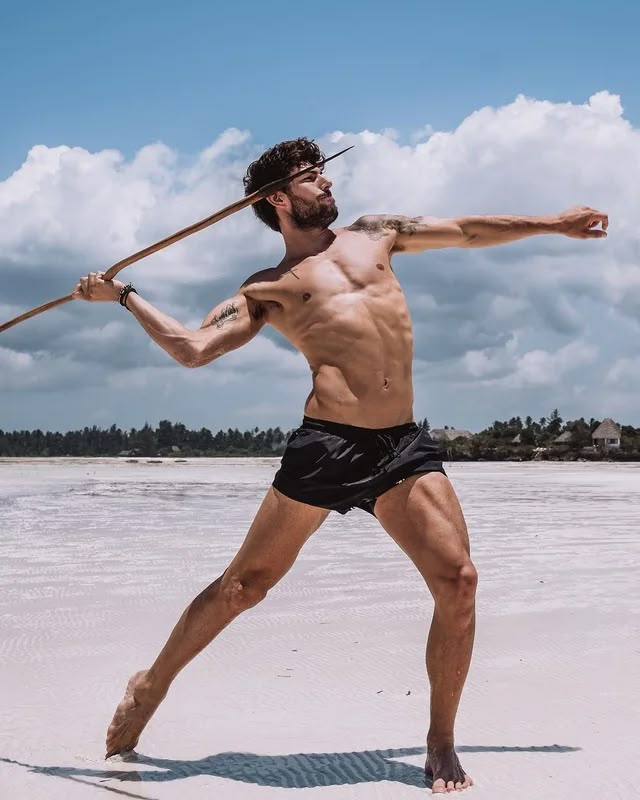 a man holding a baseball bat on top of a beach