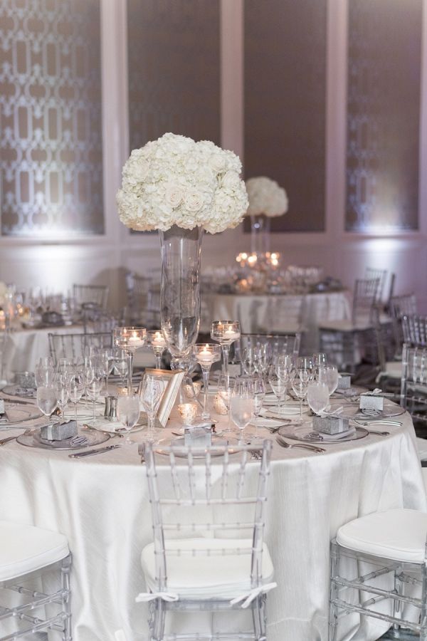 the table is set with silverware and white flowers in tall vases on each side