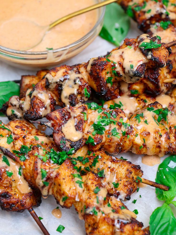 chicken skewers with sauce and greens on the side