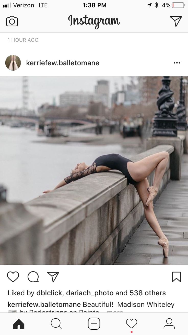 a woman in a black leotard is leaning on a wall by the water