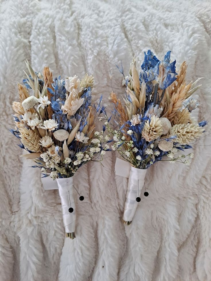 two white vases with blue and gold flowers in them sitting on a furnishing