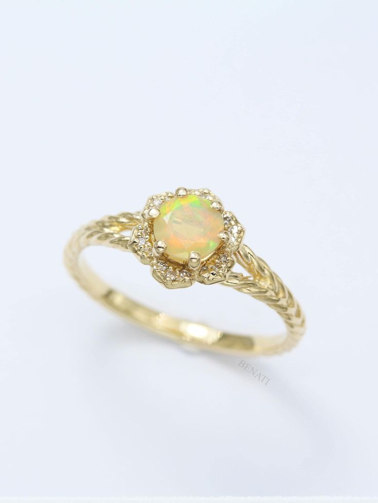 a yellow gold ring with an opal stone in the center and two diamonds on each side