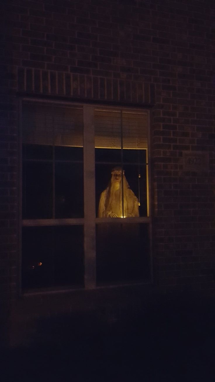 a person in a window at night with a light shining on their face and head