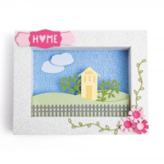 a white frame with a house and flowers on it