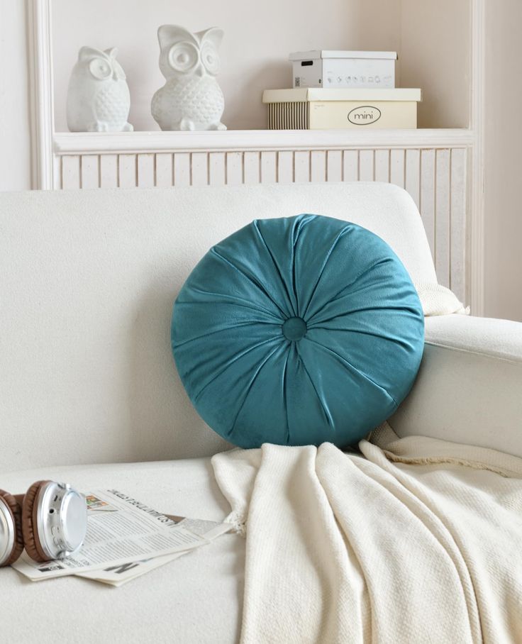 a blue pillow sitting on top of a white couch next to a stack of books