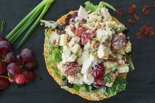 a sandwich with grapes, celery and chicken salad on it next to green onions