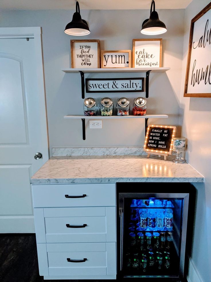 an ice chest in the corner of a room with shelves above it and two framed pictures on the wall