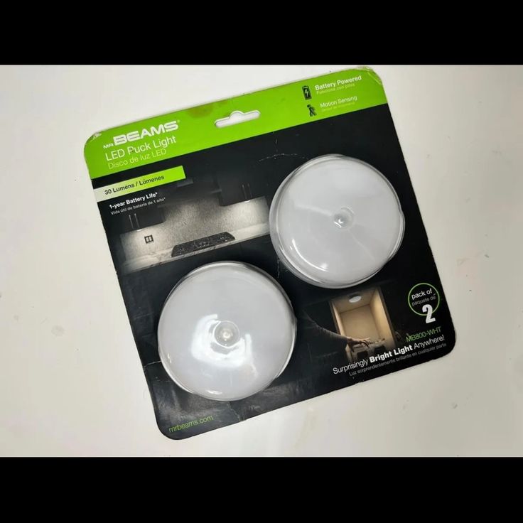 two white lights sitting on top of a table next to each other in front of a package