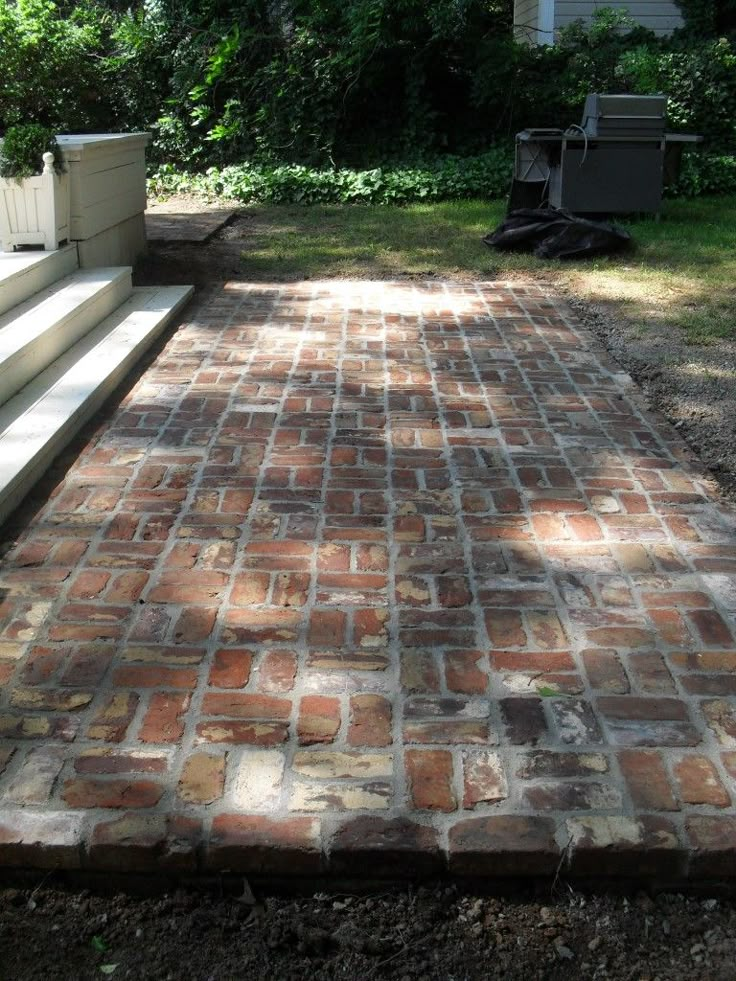 a brick walkway in front of a house with steps leading up to the back door