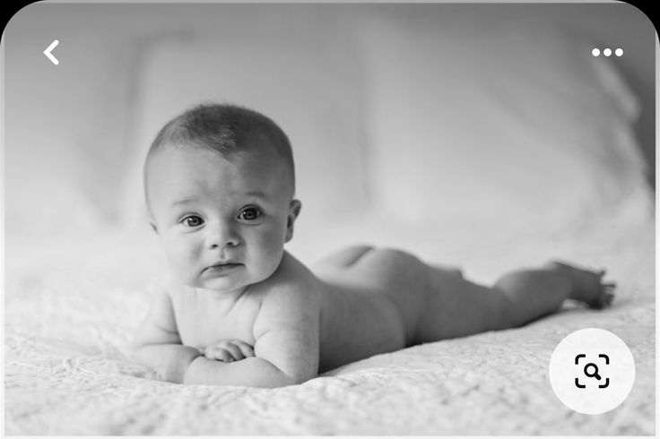 a baby laying on its back in black and white