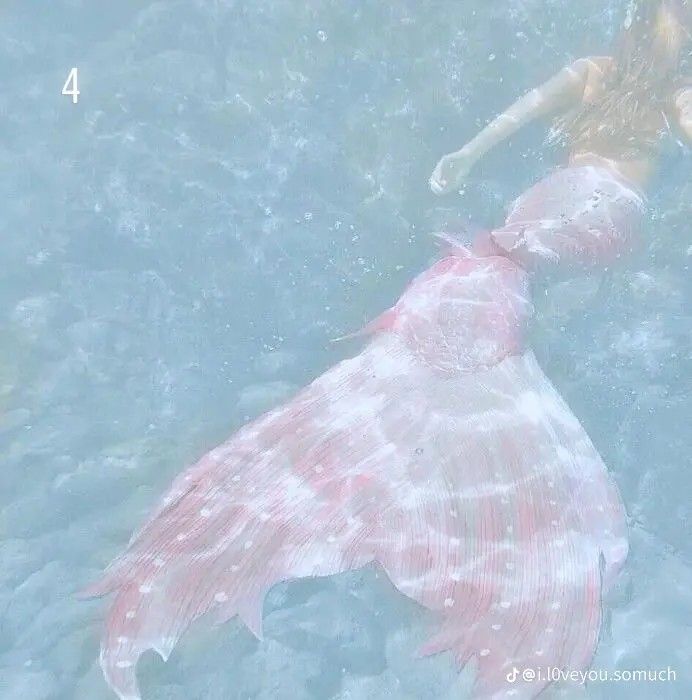 a woman swimming in the ocean with a large pink fish behind her and another person standing next to it